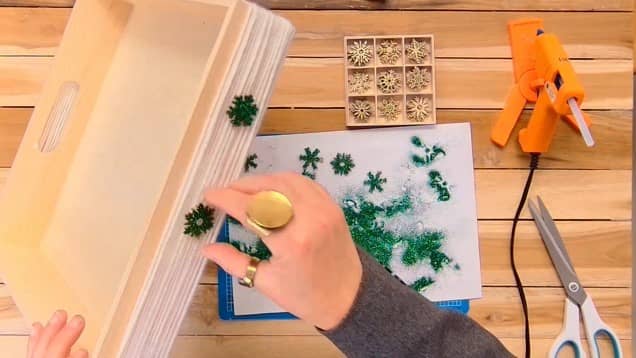 Coller des paillettes sur les flocons de neige du centre de table pour Noël