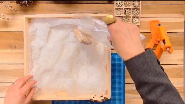 Ajouter des flocons de neige en plastique sur la ouate du centre de table de Noël